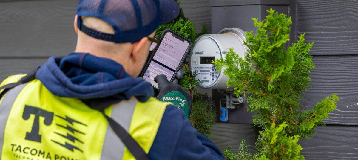 Field investigator checking a power meter on the side of a house.