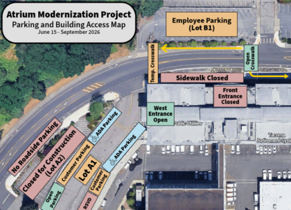 Aerial map showing temporary parking and building access changes during the Atrium and Entrance Modernization Project. The main front entrance and adjacent sidewalk are marked closed. A temporary crosswalk directs pedestrians from parking lot A1 to the temporary public entrance on the west side of the building. Customer and visitor parking spaces, including accessible parking, are highlighted in A1. Construction staging and no parking areas are marked in red near lot A2. Employee parking is identified north of the building. Arrows indicate open vehicle access routes and building access to the east side only.