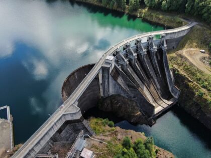 Aerial view of Mayfield Dam on the Cowlitz River, showing the concrete dam, spillway gates, reservoir and surrounding forested landscape.