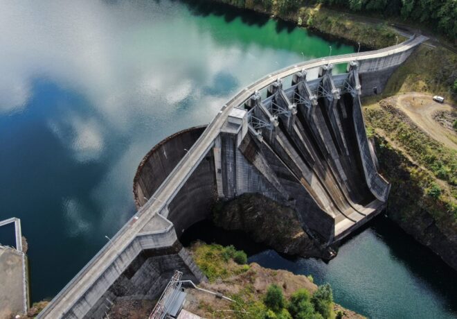 Aerial view of Mayfield Dam on the Cowlitz River, showing the concrete dam, spillway gates, reservoir and surrounding forested landscape.