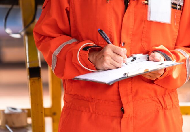 Safety officer writing and checking off items on checklist document during an inspection.