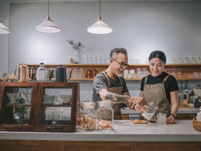 asian chinese senior male barista teaching his daughter making coffee at cafe counter