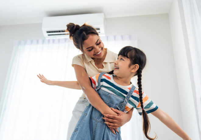 Parent and child relaxing and playing together in a living room at home, with an air-conditioned indoor environment.