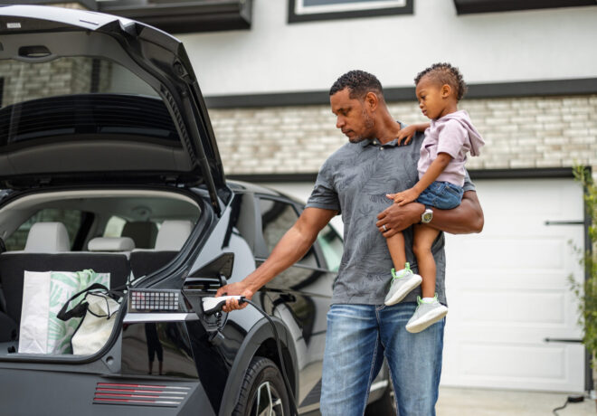 Father and son charging an electric vehicle at home.