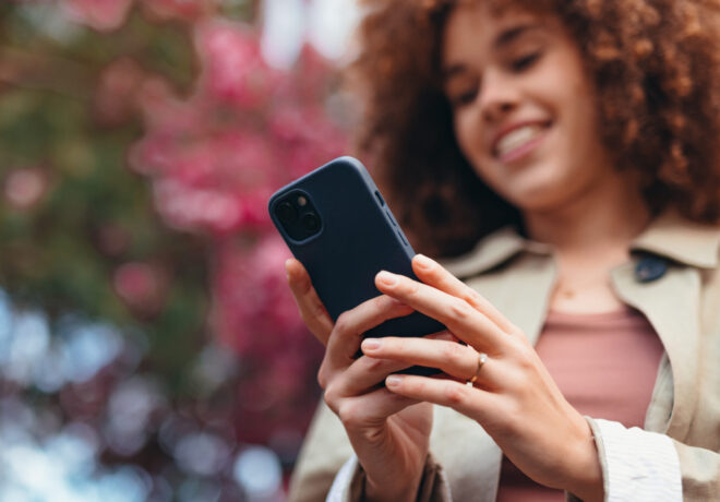 Young woman using smartphone with blurred background of pink flowers