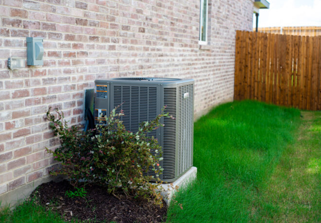 An Outdoor HVAC unit and wall mounted electrical boxes installed alongside modern brick home,