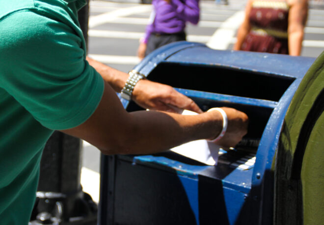 Image of someone putting a mail in a mail receptor.