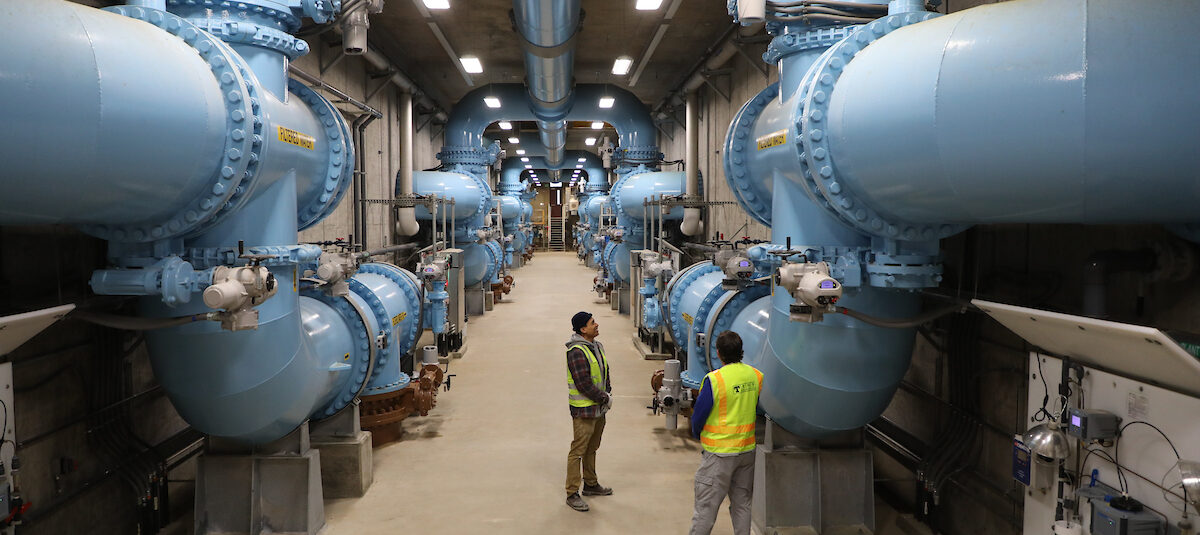 Inside Green River Headworks shows large blue water mains and employees standing below in safety vests.