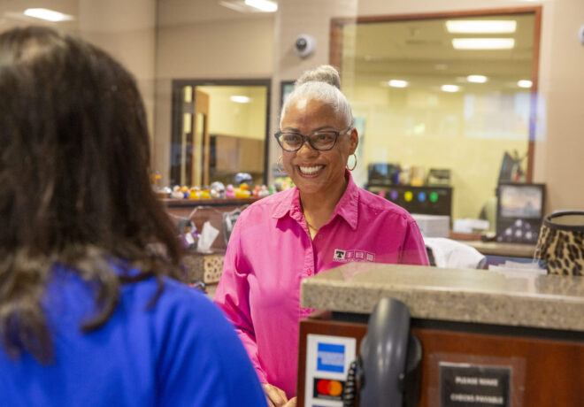Female customer service representative assisting a customer standing at the counter.