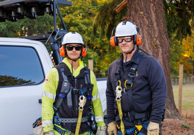 Two crew members wearing harnesses and safety equipment.