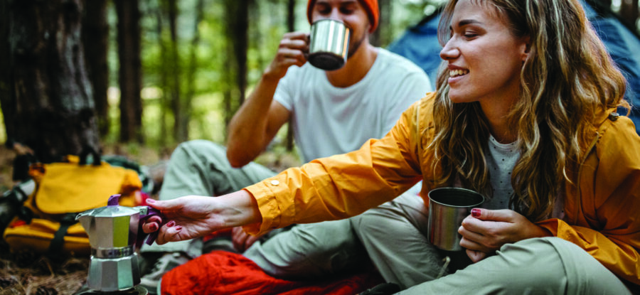 Young couple making coffee during hiking