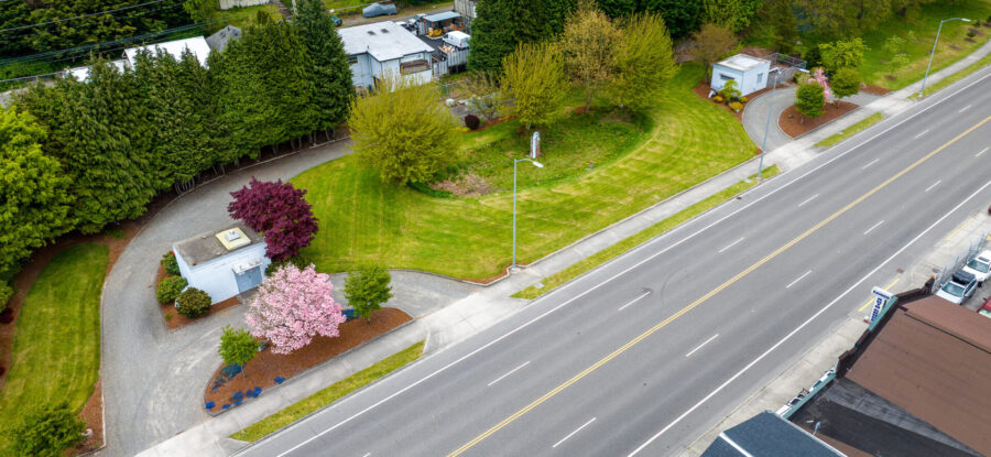Aerial view of a landscaped Tacoma water utility site beside a multilane road, surrounded by trees and residential buildings.