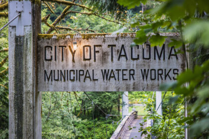 Weathered “City of Tacoma Municipal Water Works” sign surrounded by mossy forest and marking the start of the Green River Watershed.