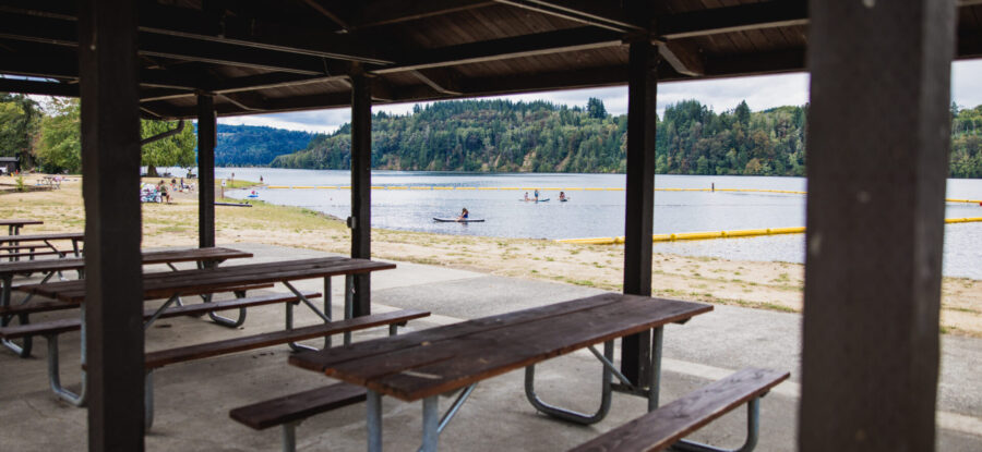 View of the picnic tables in the kitchen shelter, overlooking Mayfield Lake Park and the water.