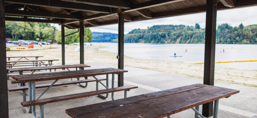 View of the picnic tables in the kitchen shelter, overlooking Mayfield Lake Park and the water.