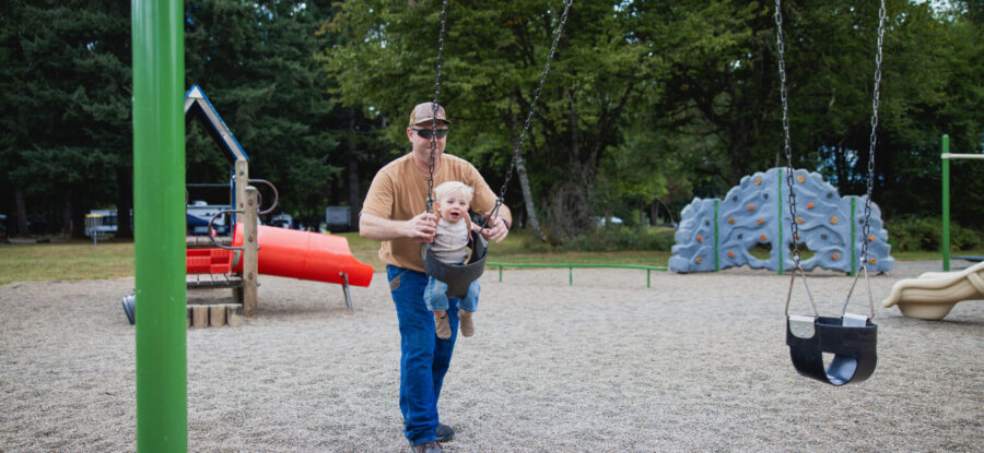 father pushing son on swing