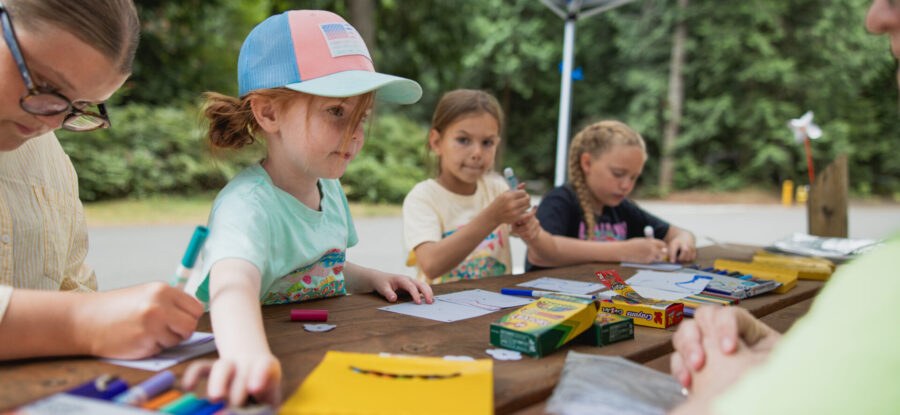 kids doing crafts by a camper with the camp host