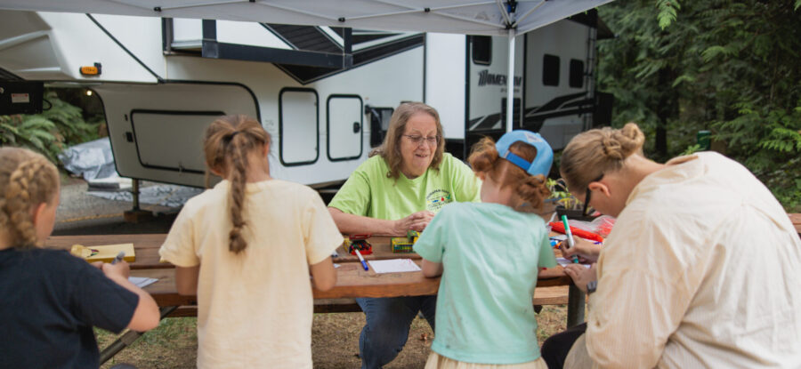 kids doing crafts by a camper with the camp host